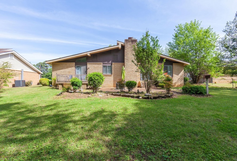 Brick exterior featuring a deck, a patio, and a sloped roofline