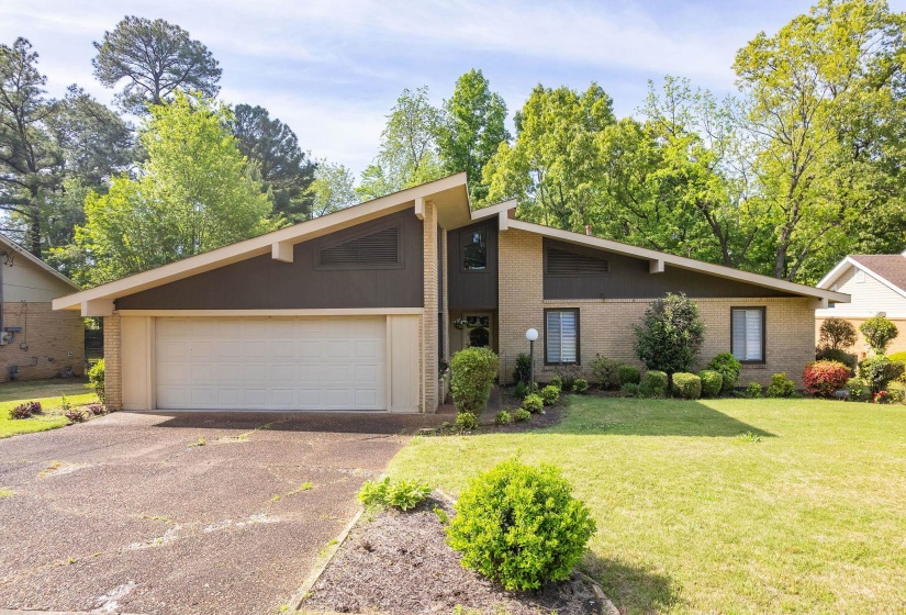 Mid-century modern exterior featuring a distinct roofline, brick façade, and an attached two-car garage