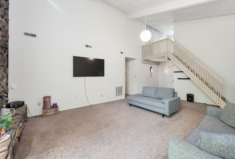 Living room featuring a vaulted ceiling and a stone-faced fireplace