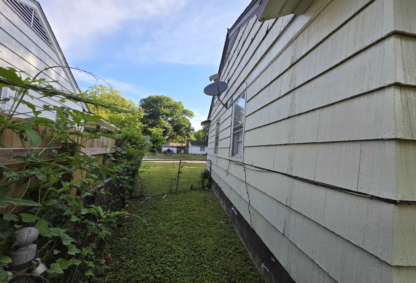 Side exterior showcasing horizontal siding, a framed window, and a gabled roofline