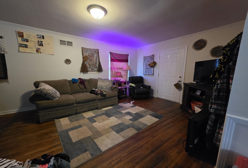 Spacious living area featuring wood-finish flooring, white baseboards, and crown molding