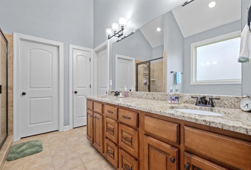 Expansive vanity featuring dual undermount sinks, a granite-finish countertop, and rich wood cabinetry