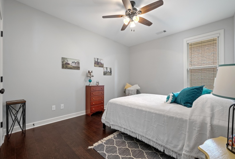 Neutral-toned room featuring a window with blinds, dark wood-finish flooring, and white baseboards