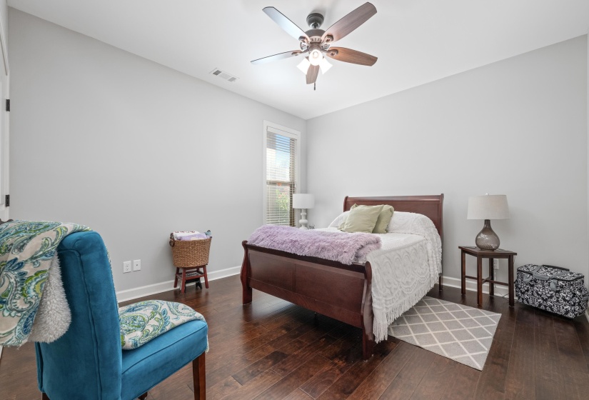 Spacious room featuring wood-finish flooring, a contemporary ceiling fan with integrated lighting, and a window with horizontal blinds