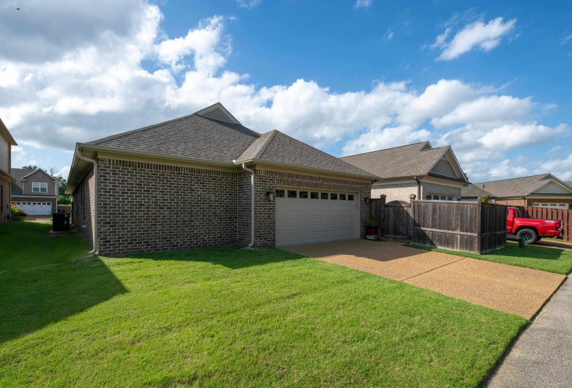 Brick exterior featuring a two-car garage with an overhead door, gravel driveway, and a manicured lawn