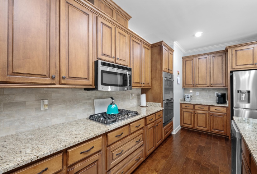 Kitchen featuring wood cabinetry, stainless steel appliances, a gas cooktop, light-toned countertops, and wood-finish flooring