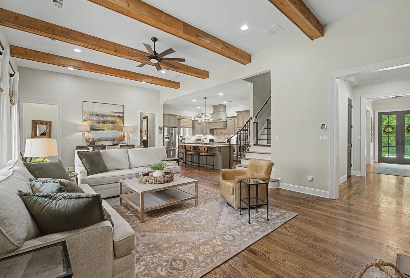 Spacious living area featuring exposed ceiling beams, recessed lighting, and rich wood-finish flooring