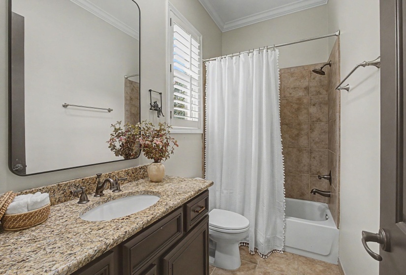 Bathroom featuring a granite-finish countertop, dark wood-finish vanity, undermount sink, and a framed mirror