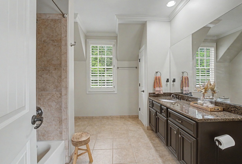 Bathroom with a spacious vanity featuring a speckled countertop and dual sinks