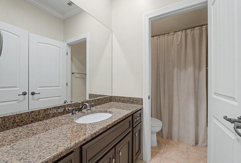 Bathroom featuring a dark wood vanity with a granite countertop, undermount sink, and polished chrome faucet