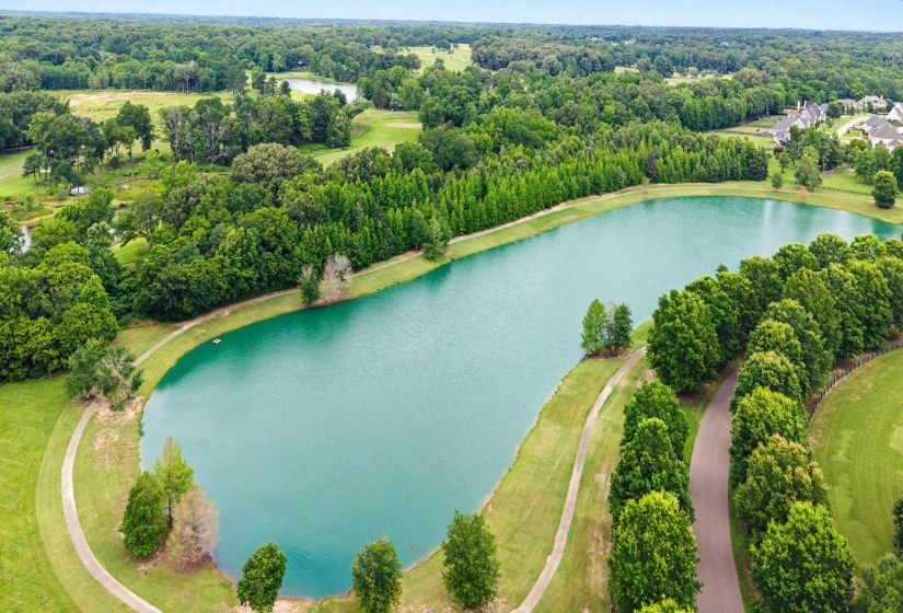Expansive lakefront property with mature tree lines and paved pathways