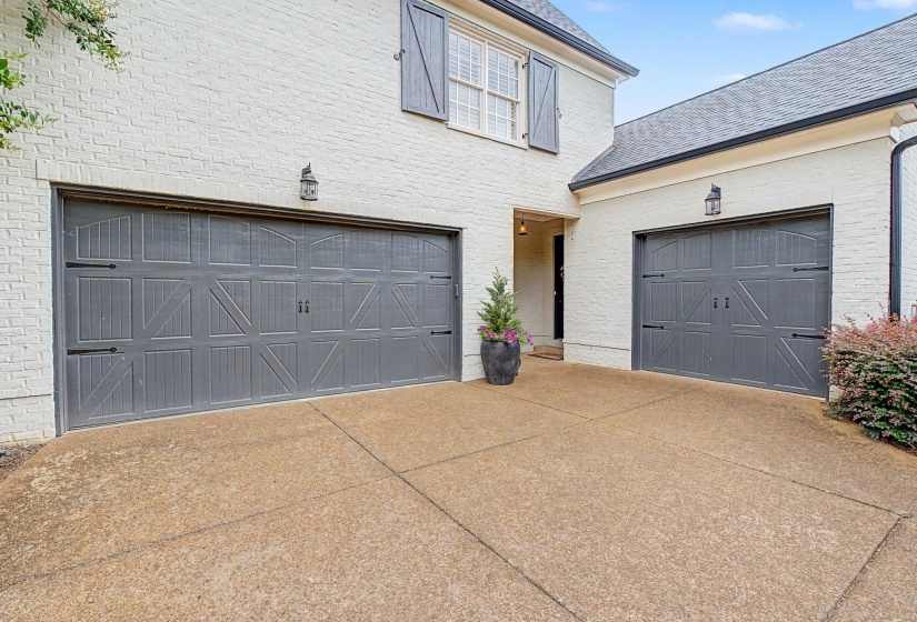 Exterior brick facade with two garage doors featuring decorative hardware and sconce lighting