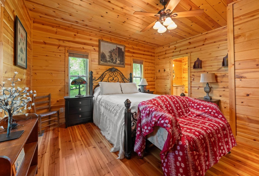 Wood-paneled room featuring wood-finish flooring, a ceiling fan with integrated lighting, and multiple windows