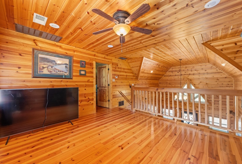 Wood-paneled room featuring wood-finish flooring, a ceiling fan with integrated lighting, recessed lighting, and a wood railing