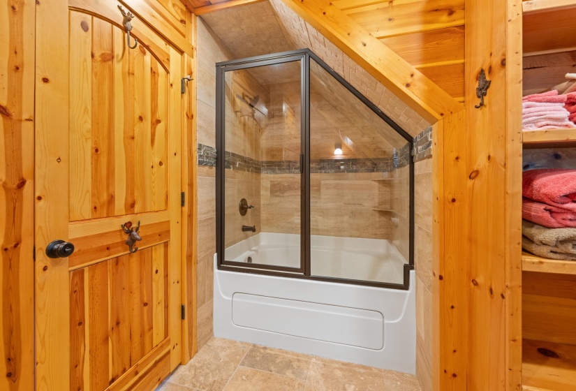Bathroom featuring a white tub with a glass and bronze-tone enclosure
