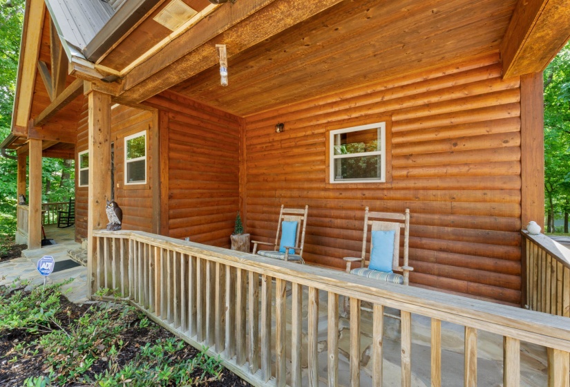 Log-style exterior featuring a covered porch with a wood-finish ceiling, natural wood siding, white-framed windows, and a metal roof