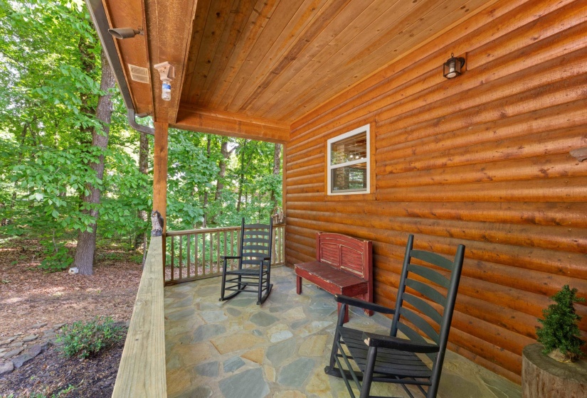 Covered porch featuring log-cabin style siding and a wood-finish ceiling