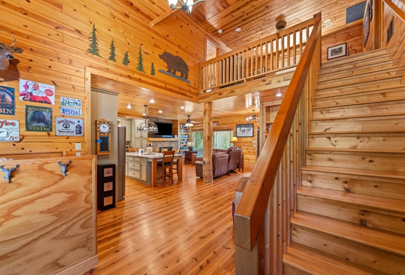 Two-story interior showcasing extensive wood-finish walls and ceilings, a wooden staircase, and a second-story balcony