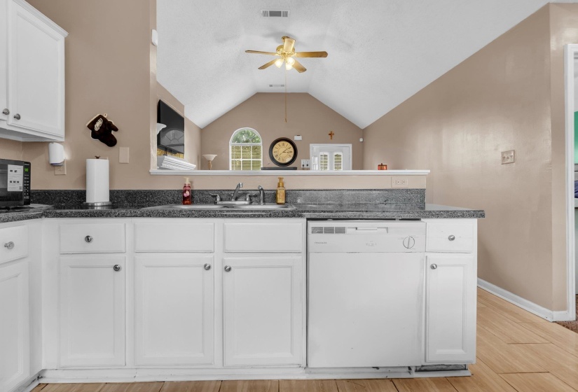 Kitchen featuring white cabinetry, dark speckled countertops, and a stainless steel sink with a single-handle faucet