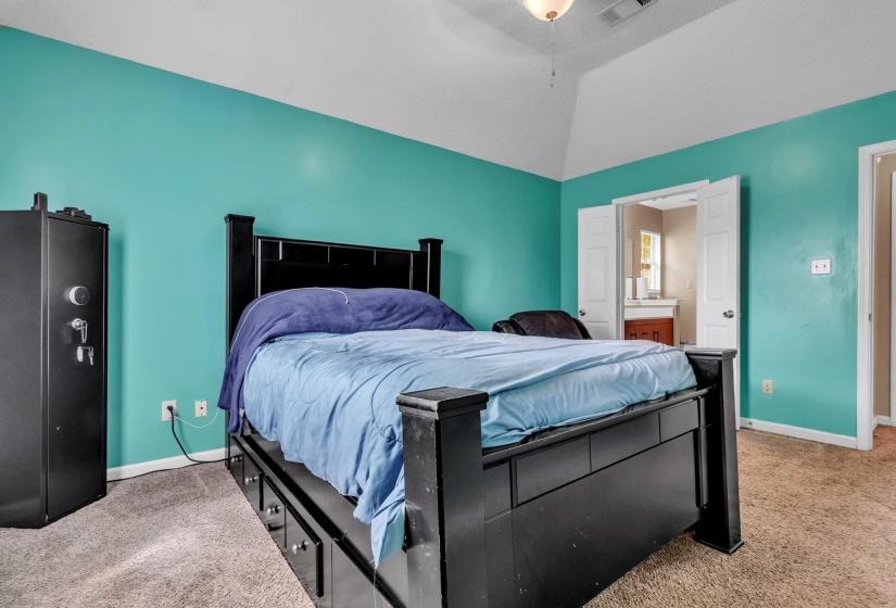 Vaulted ceilings highlight this room featuring a teal accent wall and carpeted flooring