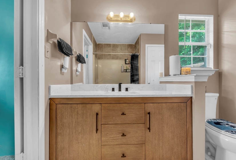 Bathroom featuring a wood-finish vanity with a light-colored countertop and a rectangular sink