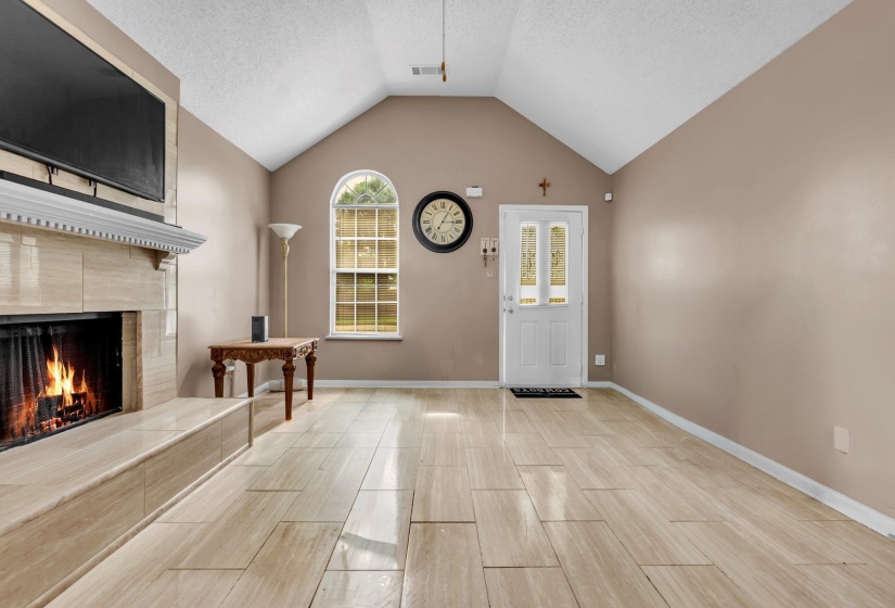 Living area featuring a vaulted ceiling, light-toned wall paint, and wood-finish tile flooring