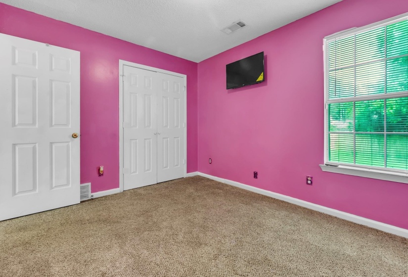 Spacious room featuring carpet flooring, crisp white trim, and a window with blinds