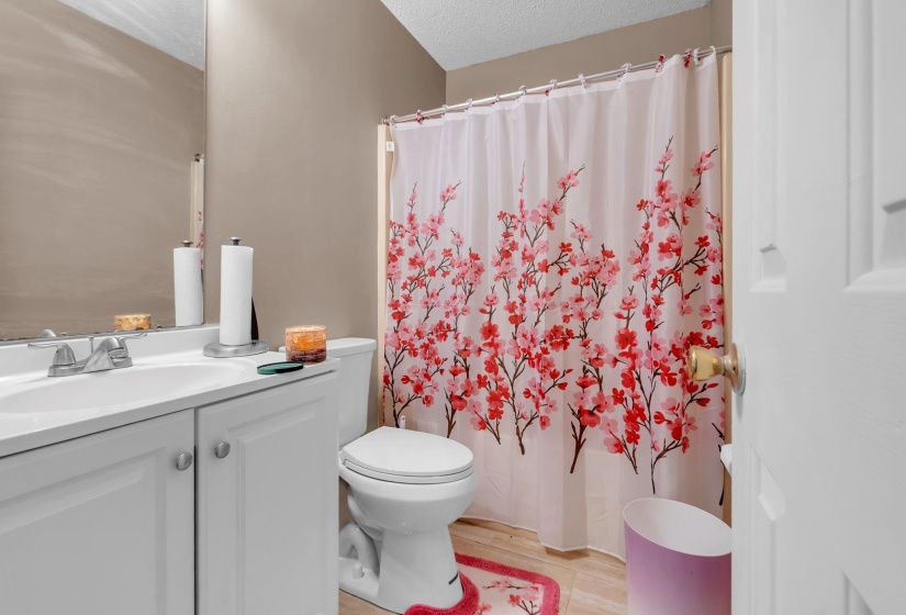 Bathroom featuring a single vanity with a white countertop and integrated sink, a white two-piece toilet, and light-toned tile flooring