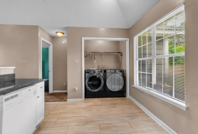 Utility area featuring wood-finish flooring, a large window with blinds, and a built-in closet with shelving