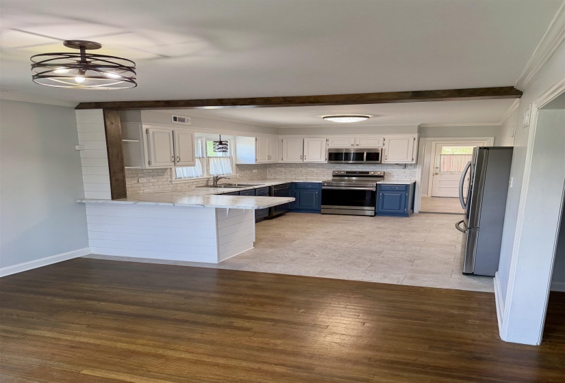 Well-appointed kitchen featuring white upper cabinetry, blue lower cabinetry, stainless steel appliances, and a white subway tile backsplash