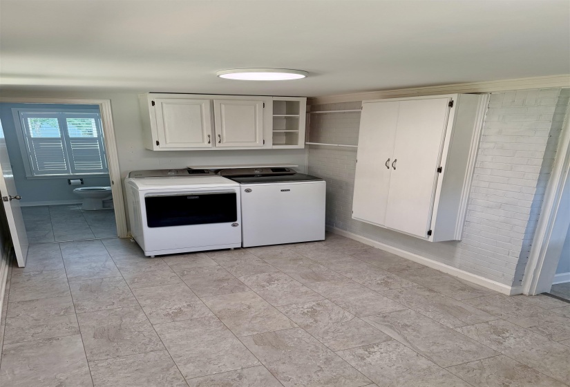 Laundry area featuring tile flooring, white wall cabinetry, and a full-height storage cabinet