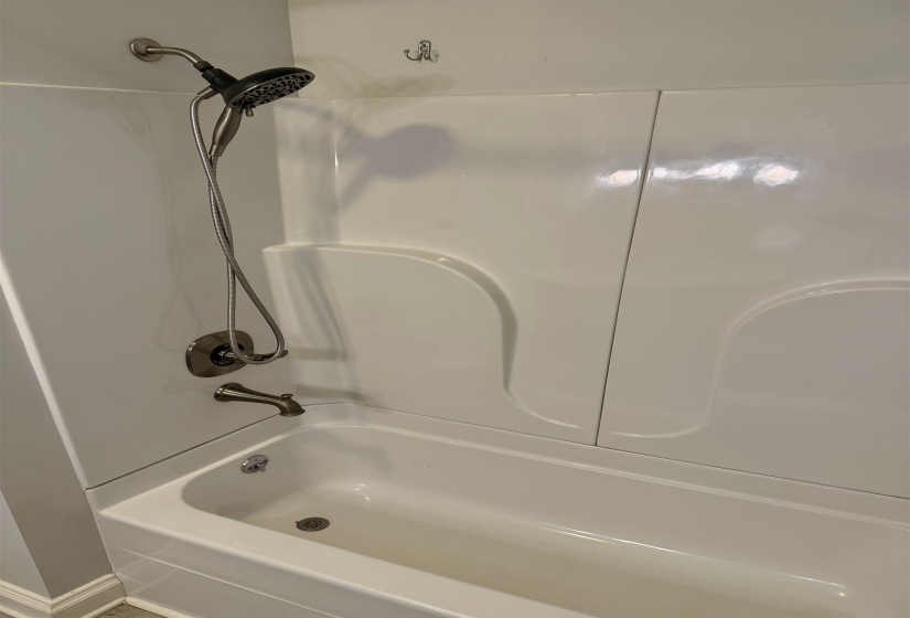 White tub and shower combination with a brushed nickel shower head and faucet