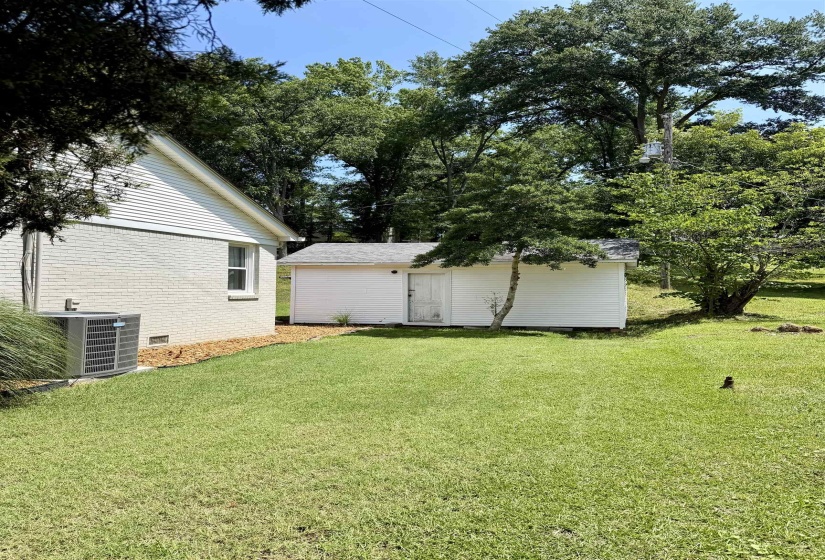 Expansive green lawn featuring a white siding outbuilding with a gray shingle roof