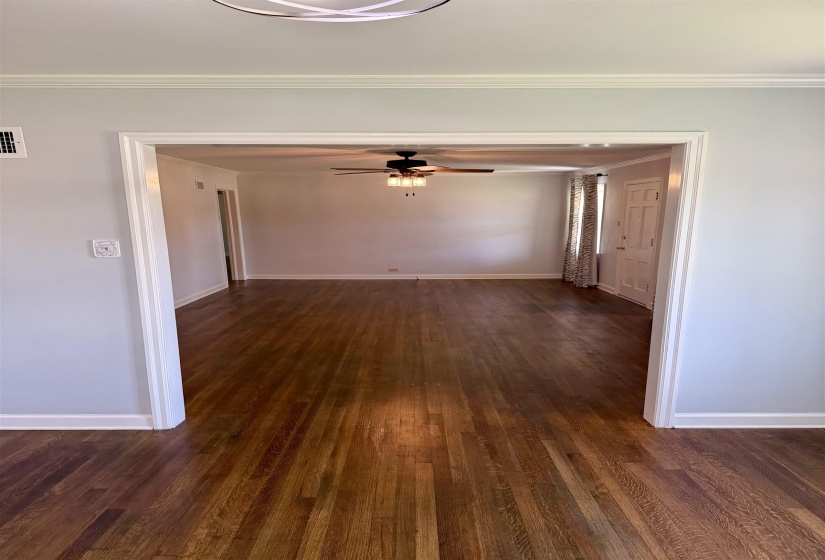 Expansive wood-finish flooring extends throughout the space, featuring a wide doorway opening