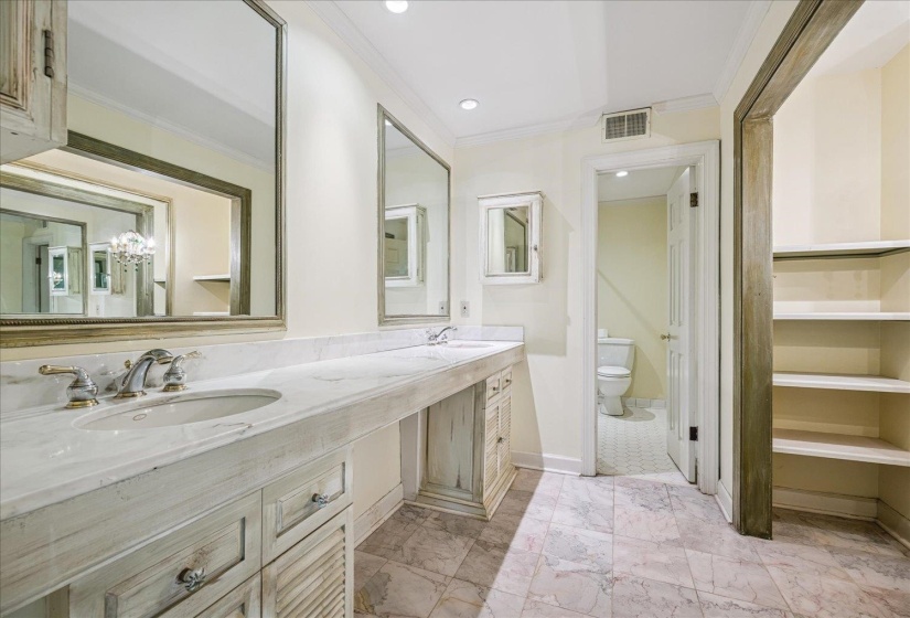 Bathroom featuring a dual vanity with undermount sinks, marble-finish countertop, and decorative framed mirrors