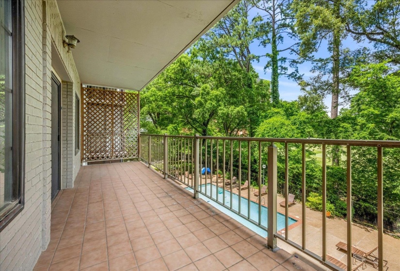 Expansive private balcony featuring terracotta-toned tile flooring, light brick exterior, and decorative lattice screen