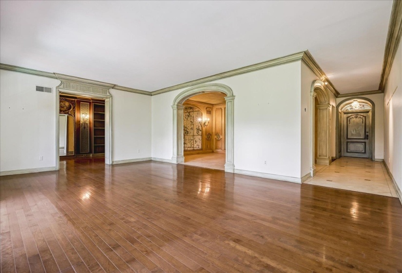 Hardwood flooring throughout a spacious room with ornate archways
