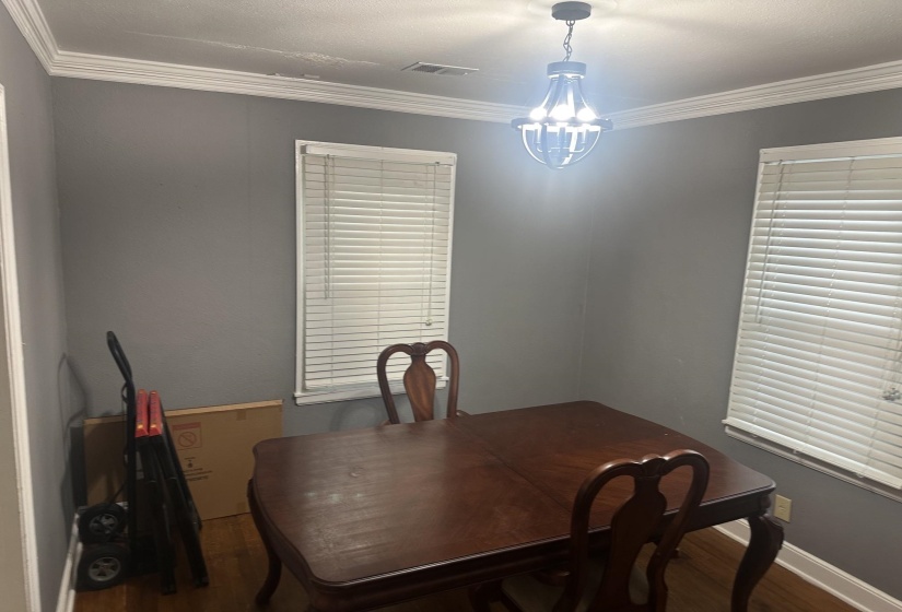 Room featuring gray walls, white crown molding, and wood-finish flooring