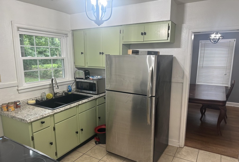 Kitchen featuring sage green cabinetry, a black double-basin sink, and granite-finish countertops