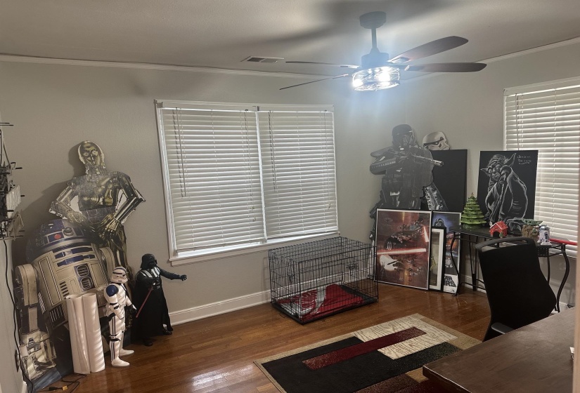 Room with wood-finish flooring, two windows with blinds, and a ceiling fan with integrated lighting