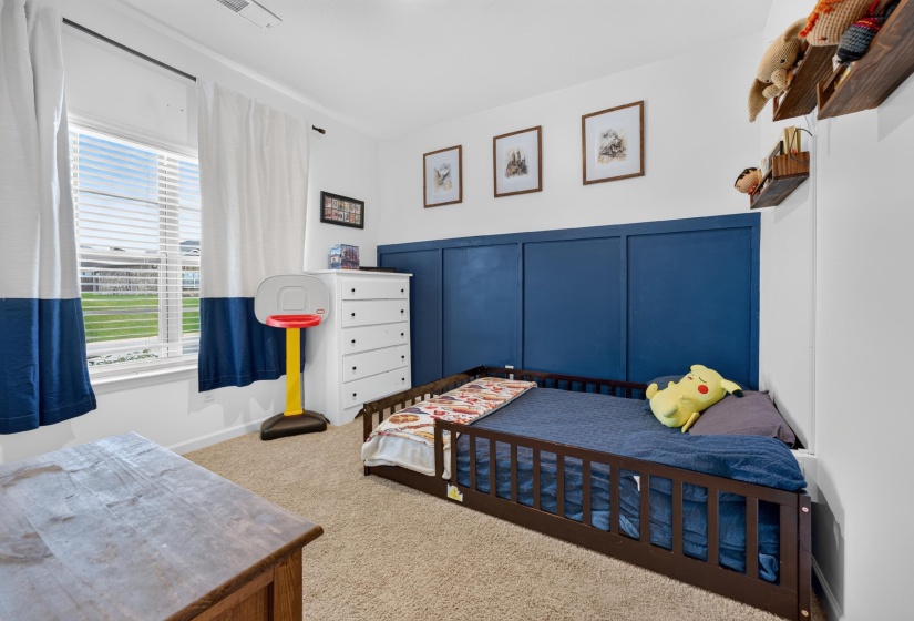 Carpeted room featuring a window with blinds, a paneled accent wall, and built-in floating shelves