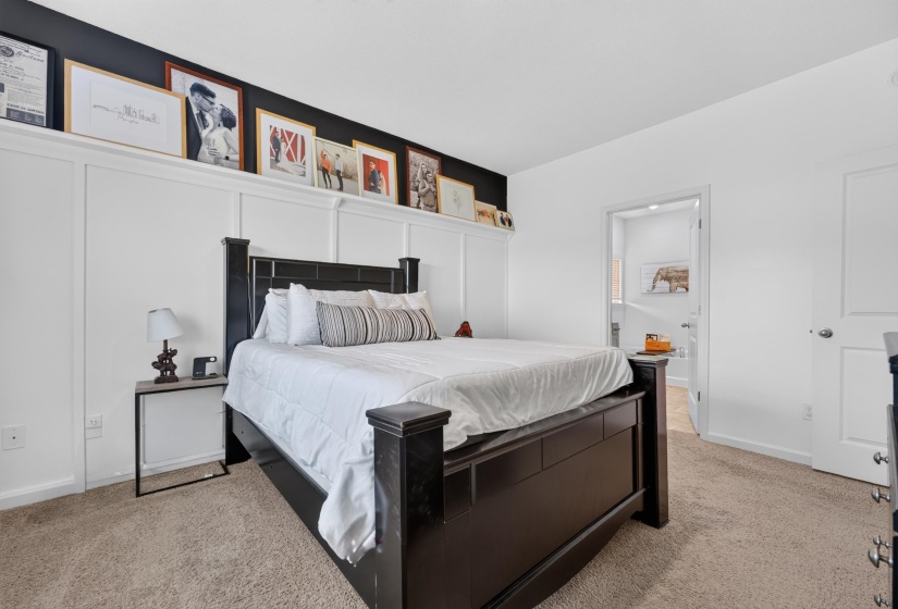 Bedroom featuring broadloom carpet and a white panel accent wall with integrated shelving