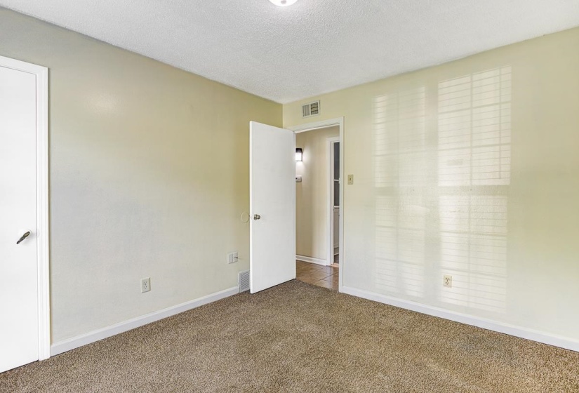 Light-filled room featuring neutral-toned carpeting, light cream wall paint, and crisp white trim