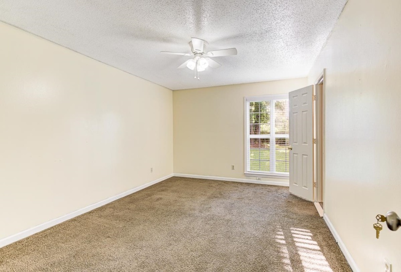 Carpeted room with neutral wall tones and a ceiling fan