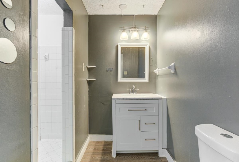 Bathroom featuring a white vanity with silver hardware, an integrated sink, shower, and a framed mirror