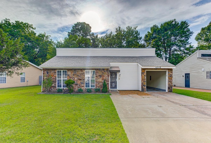 Stone veneer and horizontal siding exterior featuring multiple windows with white grids, an attached carport, and a concrete driveway