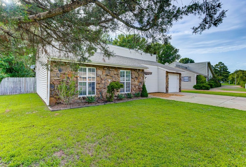 Stone and siding exterior featuring white-framed windows, a concrete driveway, and an attached garage with a white door