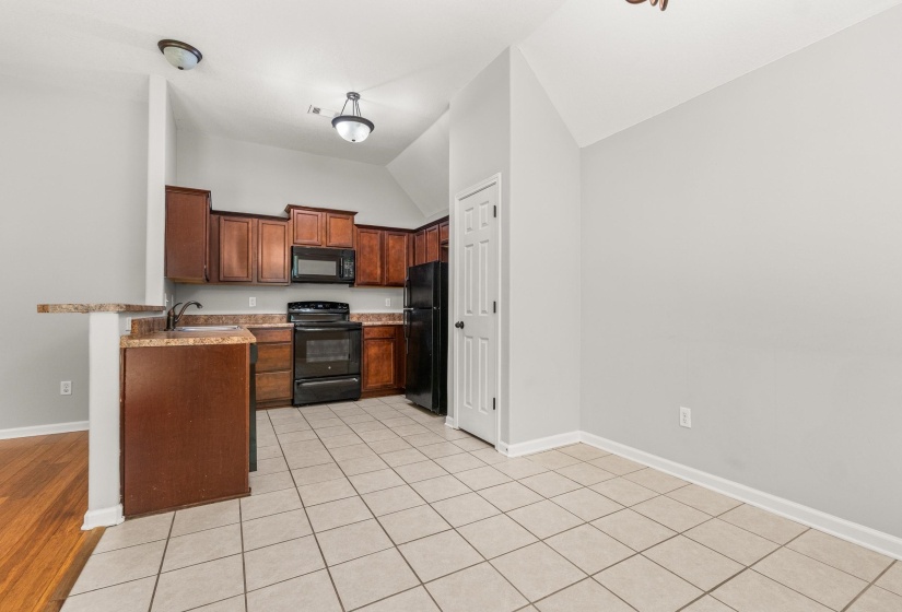Kitchen featuring wood-finish cabinetry, dark countertops, and tile flooring