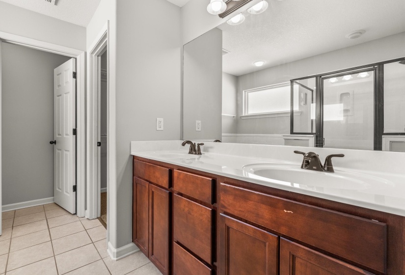 Bathroom featuring a dual vanity with wood cabinetry, white countertops, and integrated sinks