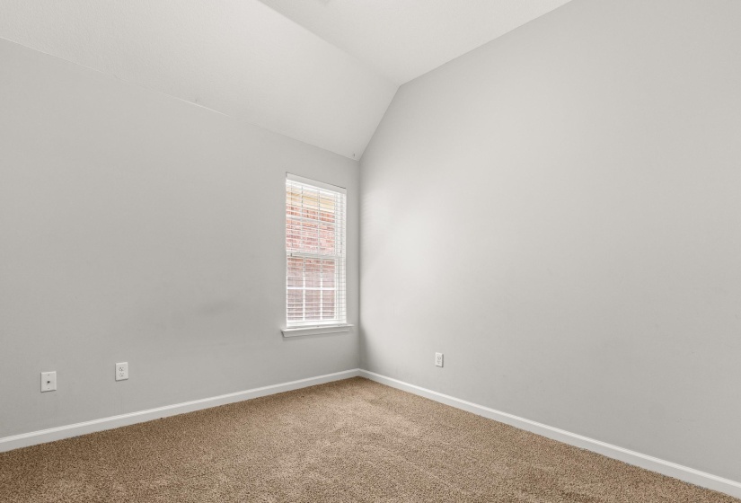 Room featuring vaulted ceilings, light gray wall paint, white trim, and a window with white blinds